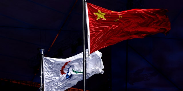 Flaga paraolimpijska jest podnoszona obok chińskiej flagi podczas ceremonii otwarcia Zimowych Igrzysk Paraolimpijskich w Pekinie 2022 na Stadionie Narodowym w Pekinie 4 marca 2022 r. w Pekinie w Chinach. 